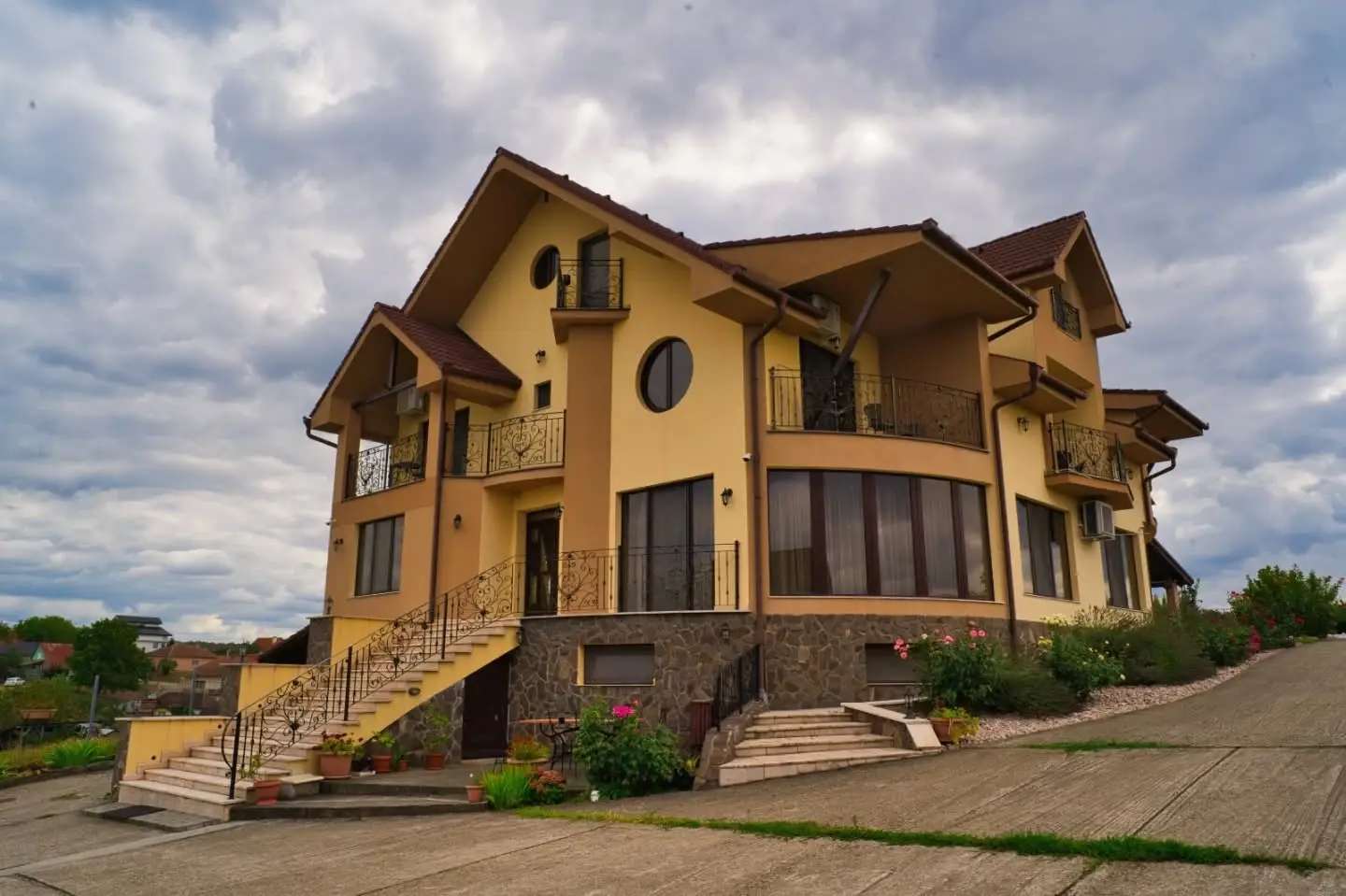 Pensiunea Neredy main villa in Băile 1 Mai, with a yellow facade, wrought-iron balconies, and a dramatic sky