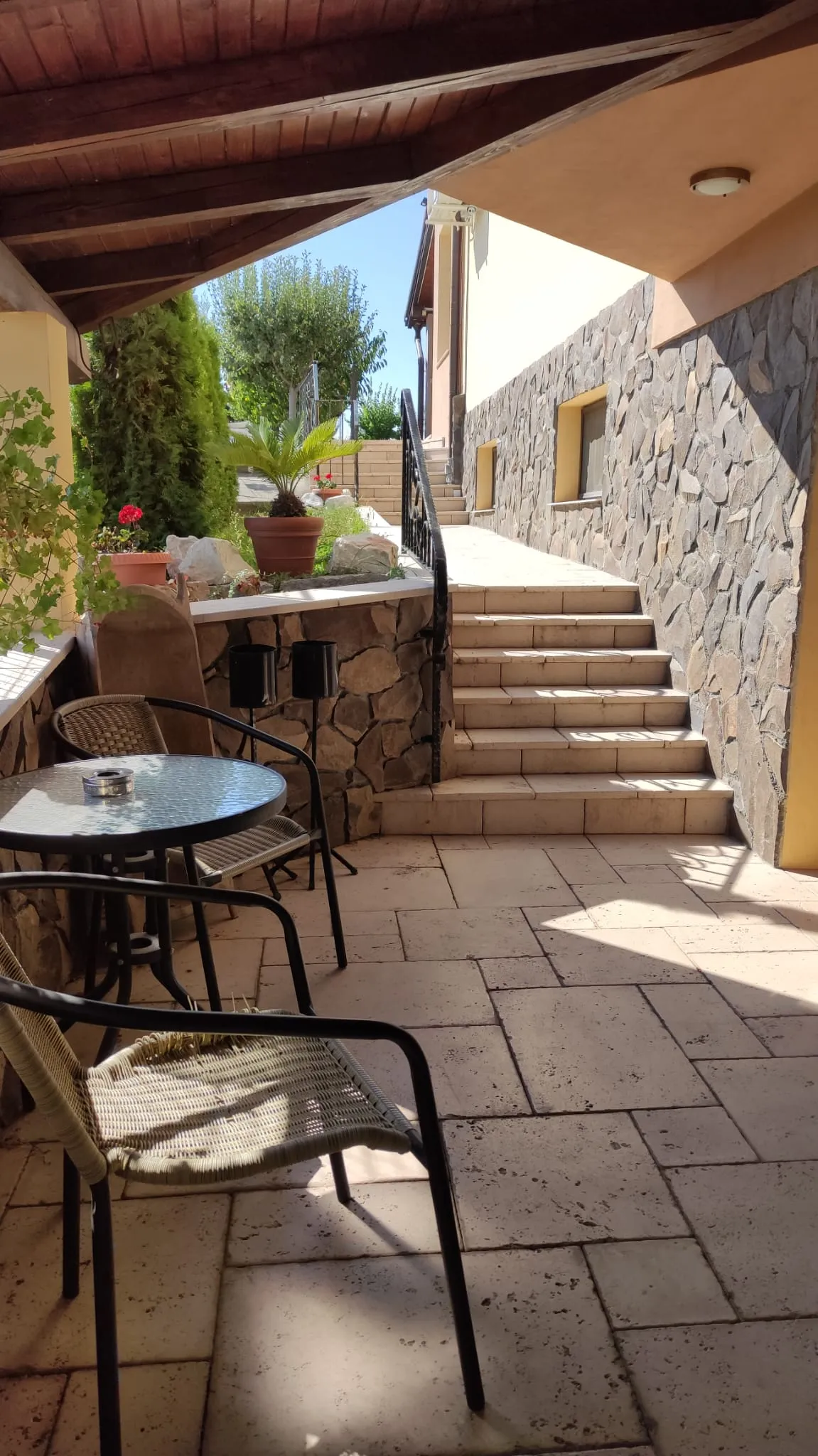 Terrace with stone steps, plants and iron furniture